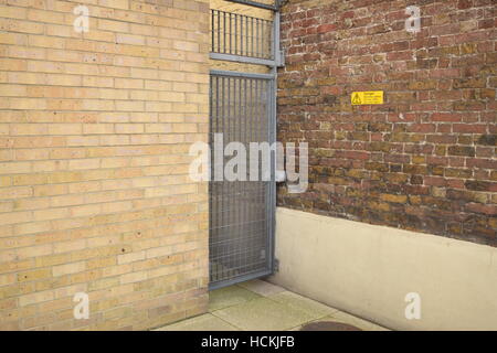 Metall-Sicherheits-Tür in eine Mauer mit einem gelben Warnschild an der Wand Stockfoto
