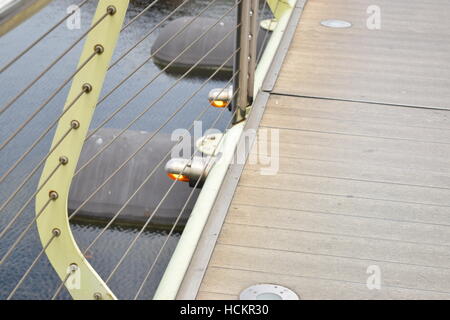 Kleine orange Lichter am Rande einer Brücke mit Blick aufs Wasser Stockfoto