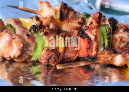 Frisch gegrillte Spieße auf einer Alufolie mit Küche im Hintergrund Stockfoto