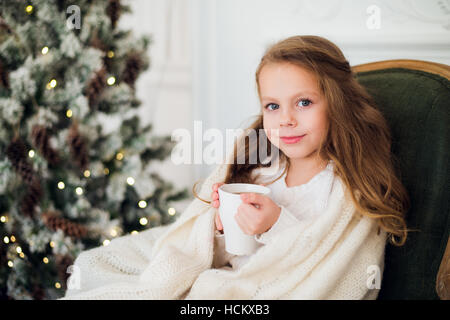 Kleines Mädchen Konsummilch Weihnachtsbaum Morgen zu Hause Stockfoto