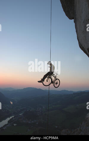 Extremsport, ein Mann Abseilen mit einem Motorrad vor dem Sonnenuntergang, Losenstein, Oberösterreich, Österreich Stockfoto