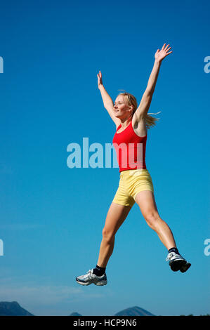 Junge blonde Frau, springen, fröhlich Stockfoto