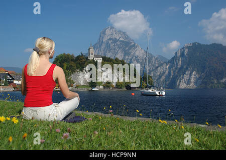 Junge blonde Frau entspannend am See Traunsee, Salzkammergut Resort Area, Upper Austria, Europe Stockfoto