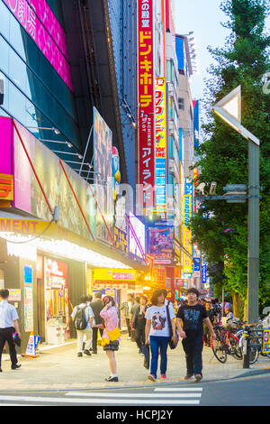 Menschen zu Fuß auf dem Bürgersteig unter vertikal speichern Zeichen und helle Lichter in Elektronik Mekka von Akihabara am Abend Stockfoto