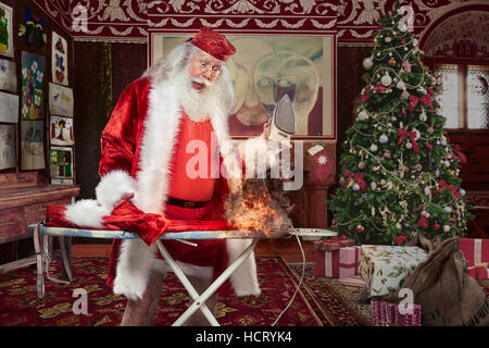 Santa Claus versuchen, seine Hose bügeln, aber es steht in Flammen. Stockfoto