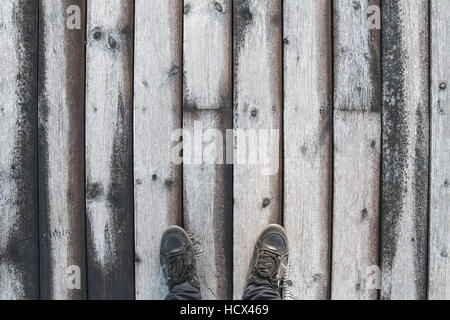 Männliche Füße in schwarzem Lederschuhe stehen alte hölzerne Pier Stock mit frost Stockfoto
