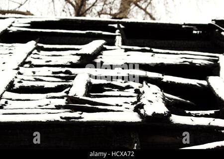 verschneite verlassenen ausgebrannten Feuer Holzhaus. Stockfoto