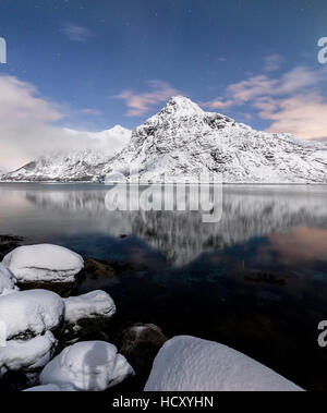 Die schneebedeckten Gipfel spiegeln sich in den kalten See unter dem Sternenhimmel, Vareid, Flakstad, Nordland, Lofoten-Inseln, Nord-Norwegen Stockfoto