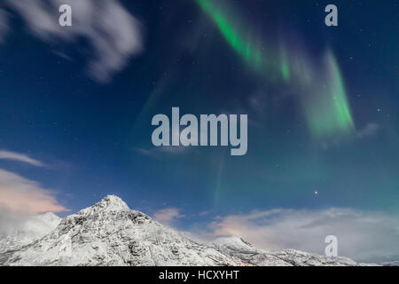 Nordlicht und Sterne leuchten auf den schneebedeckten Gipfeln, Vareid, Flakstad, Nordland, Lofoten-Inseln, Nord-Norwegen Stockfoto