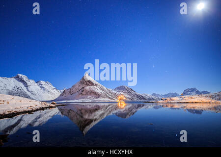 Vollmond und Sterne leuchten auf den schneebedeckten Gipfeln spiegelt sich im Meer, Volanstinden, Fredvang, Lofoten-Inseln, Nord-Norwegen Stockfoto