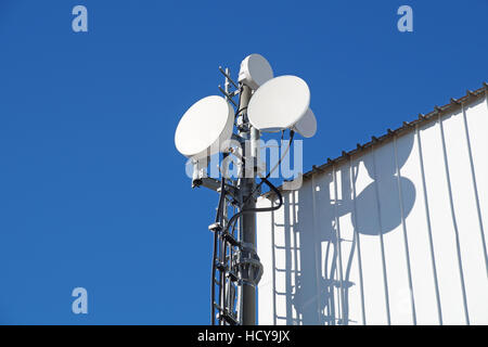 Telekommunikation-Türme mit TV-Antennen und Satellitenschüssel auf klaren, blauen Himmel Stockfoto