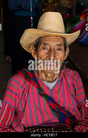 Ein 80-jähriger Bauer sitzt im Inneren der Markt in San Antonio Palopó, Guatemala, die typische Kleidung seiner Stadt, einschließlich eine Hand-Woven Shirt tragen und Stockfoto