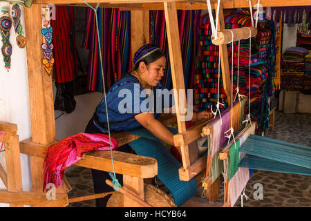 Eine Maya-Frau, trägt typische Tracht webt Stoff auf einem Fuß betätigt Webstuhl in Werkstatt in San Antonio Palopó, Guatemala. Stockfoto