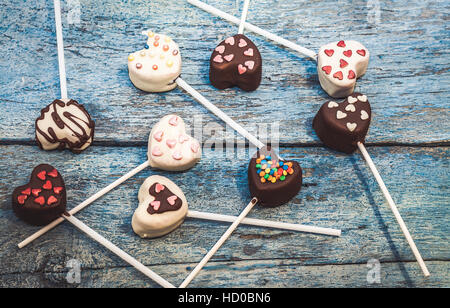 viele Cake Pops in Form Herzen liegen auf der alten blauen hölzernen Hintergrund Draufsicht. Stockfoto