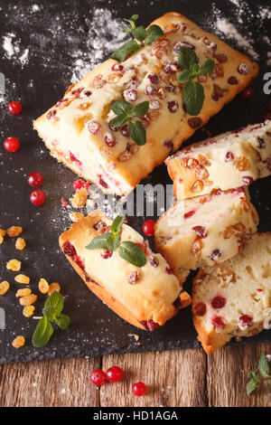 in Scheiben geschnittene Obstkuchen mit Cranberries und Rosinen mit Minze dekoriert hautnah auf dem Tisch. vertikale Stockfoto