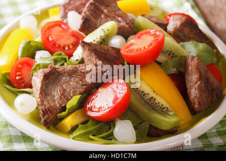 Köstlicher Salat mit Rindfleisch, Kiwi, Tomaten, Paprika und Kräutern in einer Schüssel Nahaufnahme. horizontale Stockfoto