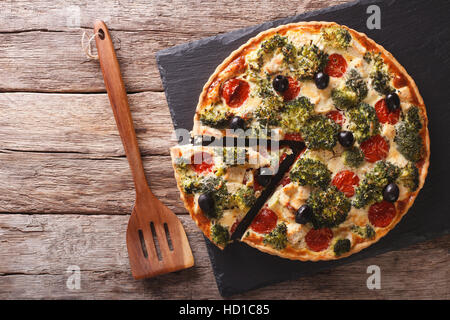 Herzhafte Kuchen: Geschnittene Quiche mit Hähnchen, Brokkoli, Tomaten und Oliven Nahaufnahme auf dem Tisch. horizontale Ansicht von oben Stockfoto
