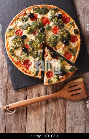 Herzhafte Kuchen: Geschnittene Quiche mit Hähnchen, Brokkoli, Tomaten und Oliven Nahaufnahme auf dem Tisch. Vertikale Ansicht von oben Stockfoto