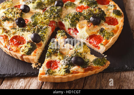 In Scheiben geschnittene Quiche mit Hähnchen, Brokkoli, Tomaten und Oliven Nahaufnahme auf dem Tisch. horizontale Stockfoto