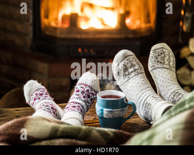 Wärmend und entspannend in der Nähe von Kamin. Mutter und Tochter mit der Tasse heißes Getränk vor Feuer. Stockfoto