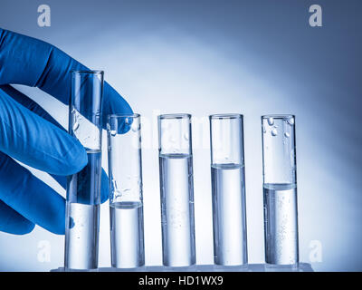 Labor-Becher in der Hand des Analytikers in Kunststoff-Handschuh. Stockfoto