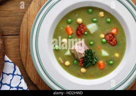 Herzhafte traditionelle holländische Erbsensuppe mit geräucherter Wurst, Roggenbrot und Speck. Oder: 'Erwtensoep met Rookworst, Roggebrood En Spek'. Stockfoto
