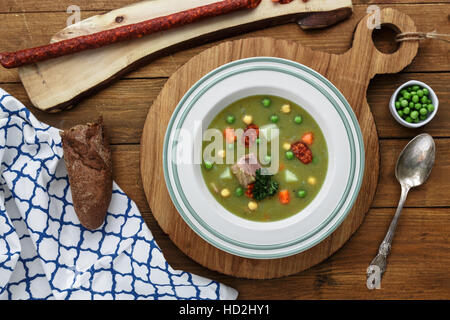 Herzhafte traditionelle holländische Erbsensuppe mit geräucherter Wurst, Roggenbrot und Speck. Oder: 'Erwtensoep met Rookworst, Roggebrood En Spek'. Stockfoto