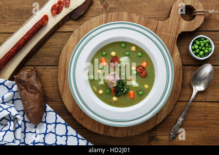 Herzhafte traditionelle holländische Erbsensuppe mit geräucherter Wurst, Roggenbrot und Speck. Oder: 'Erwtensoep met Rookworst, Roggebrood En Spek'. Stockfoto
