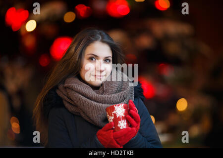 Mädchen mit langen Haaren auf europäische Weihnachtsmarkt. Junge Frau Winter-Ferienzeit genießen. Lichter der Hintergrund jedoch unscharf, Dämmerung. Stockfoto