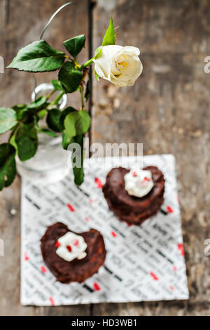 Kuchen in der Form des Herzens und eine weiße Rose. Stockfoto