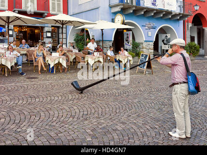 Ascona, Schweiz - 23. August 2016: Alphorn-Spieler unterhaltsam Menschen im Restaurant von Ascona am Lago Maggiore, Kanton Tessin, Schweiz. Stockfoto