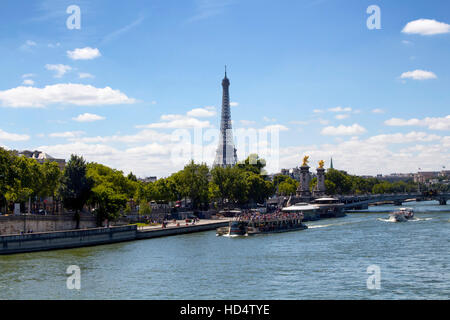 Tourboote sind am Seineufer in Paris. Bäume, Brücke Pont Alexandre III und Eiffelturm sind in der Ansicht. Stockfoto