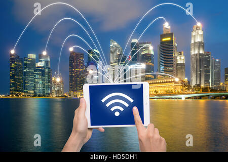 Hand, die digital-Tablette und Singapur Stadt mit Netzwerkverbindung. Smart-City-Netzwerk-Verbindung-Konzept. Stockfoto