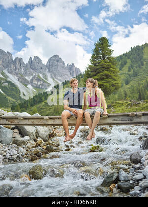 Junges Paar sitzt auf Brücke, Kemater Alm, Tirol, Österreich Stockfoto