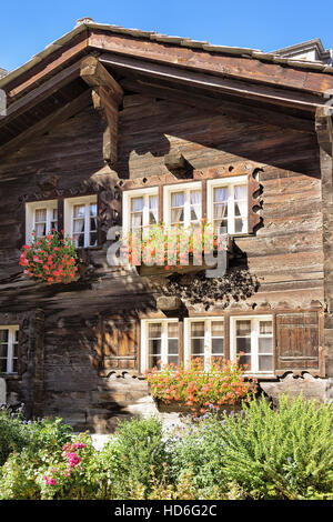 Traditionelle Schweizer Chalet mit Blumen auf dem Balkon in Zermatt Resort Dorf der Schweiz im Sommer Stockfoto