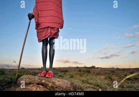 Massai-Krieger tragen traditionelle Stammes-Kleidung mit Crocs. Blauen Himmel im Hintergrund. Kenia, Afrika. Stockfoto