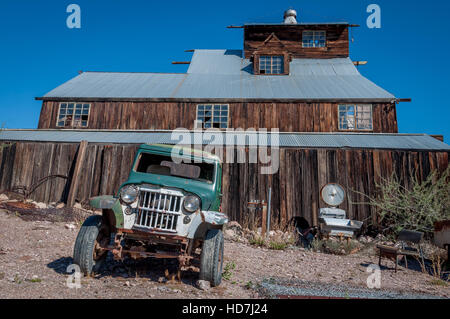 Alte grüne Abholung oder Jeep vor verlassene Mühle in Geisterstadt Techatticup Mine, Nevada geparkt. Stockfoto