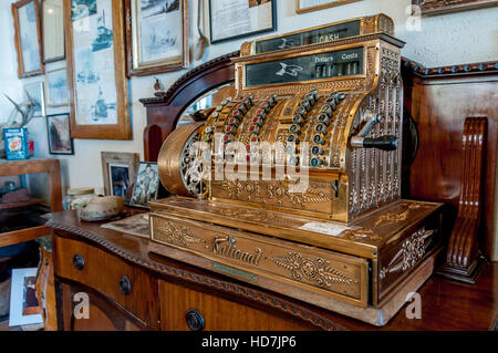 Antike Registrierkasse in Gold mit nationalen Marke in Bargeld Schublade und Hand Kurbel auf Seite auf dem Display auf antikem Holz Kommode Stockfoto