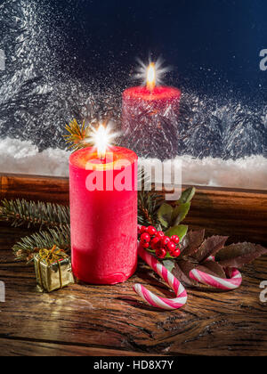 Weihnachtskerze, Tanne Zweig, Zuckerstangen und gefrorene Fenster im Hintergrund. Stockfoto