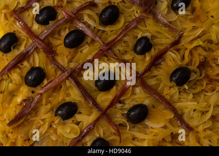 Sardellen-Gitter und Oliven auf gekochten Zwiebeln auf Blätterteig bei Pissaladiere, kochbereit hautnah. Stockfoto