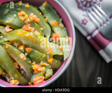 Marinierten Gurken mit Karotten in einer Keramikschale auf der Tischfläche. Die Aussicht von oben. Stockfoto
