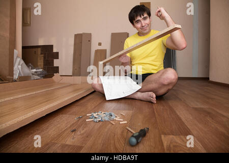 Junger Mann am Boden Montage Flatpack Schrank Stockfoto