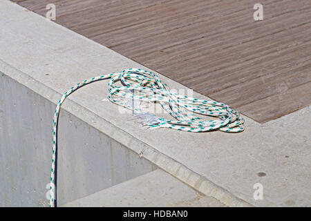 Aufgewickelt, Liegeplatz Linie um Klampe auf einem hölzernen Dock gebunden. Stockfoto