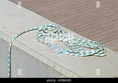 Aufgewickelt, Liegeplatz Linie um Klampe auf einem hölzernen Dock gebunden. Stockfoto