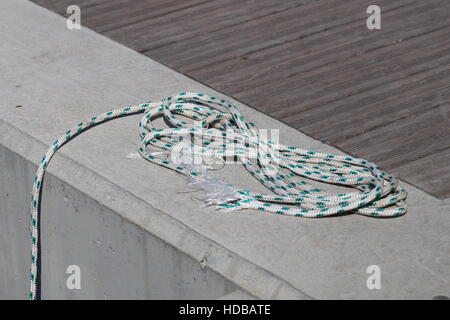 Aufgewickelt, Liegeplatz Linie um Klampe auf einem hölzernen Dock gebunden. Stockfoto