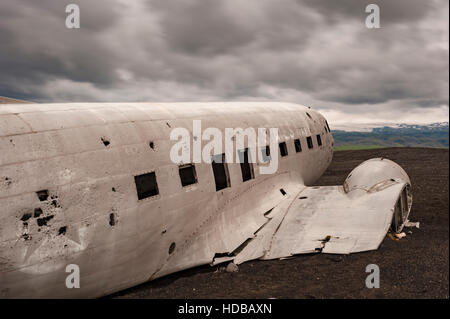 Island - Solheimasandur, United States Navy Flugzeug Wrack mit Blick auf die Berge und schwere Gewitterwolken im Hintergrund. Stockfoto