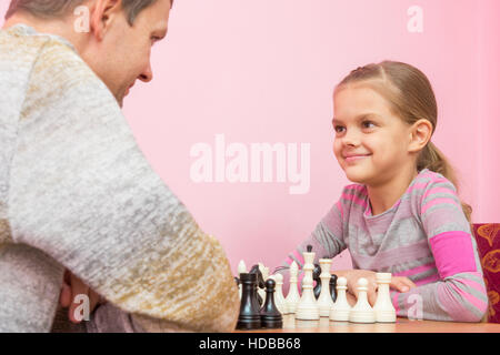 Vater und Tochter schauen gerne einander, spielen Schach Stockfoto