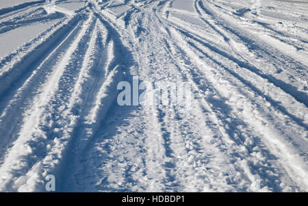 Viele Ski- und Auto-Spuren im Schnee Stockfoto