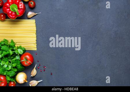 Nudeln, Gewürze und Gemüse auf Schiefer Hintergrund - kochen Zutaten für italienische Küche. Kopieren Sie Raum für Test. Ansicht von oben Stockfoto