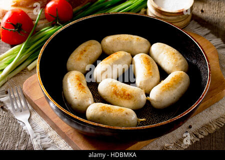 Hausgemachte gebackene gegrilltes Fleisch Huhn Wurst in einer gusseisernen Pfanne auf einem rustikalen Hintergrund. Stockfoto